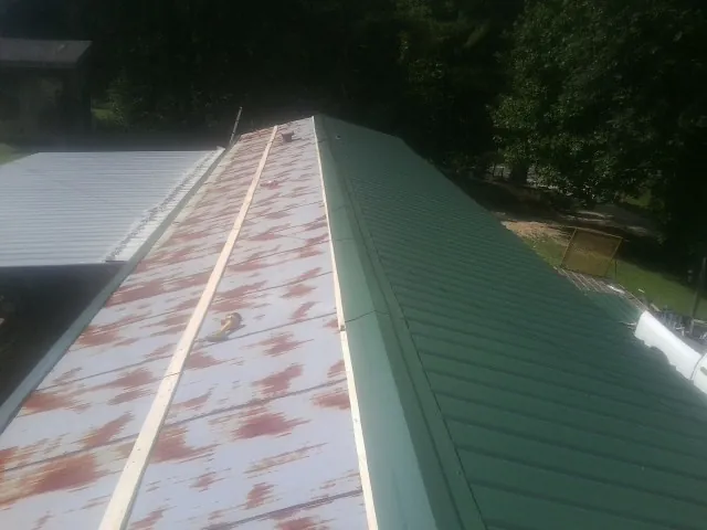 Old rusted panels beside newly installed green metal roofing — Wind Damage Roof Repair by Roofing Brothers in Boulder City