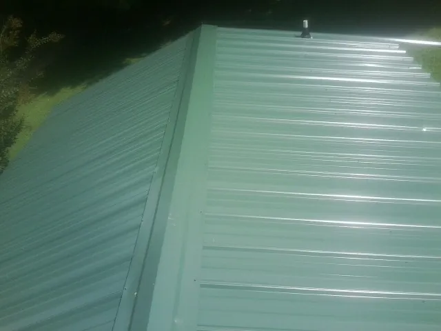 New green metal panels meeting at the ridge of a roof — Flat Roof Repair work by our crew in Boulder City