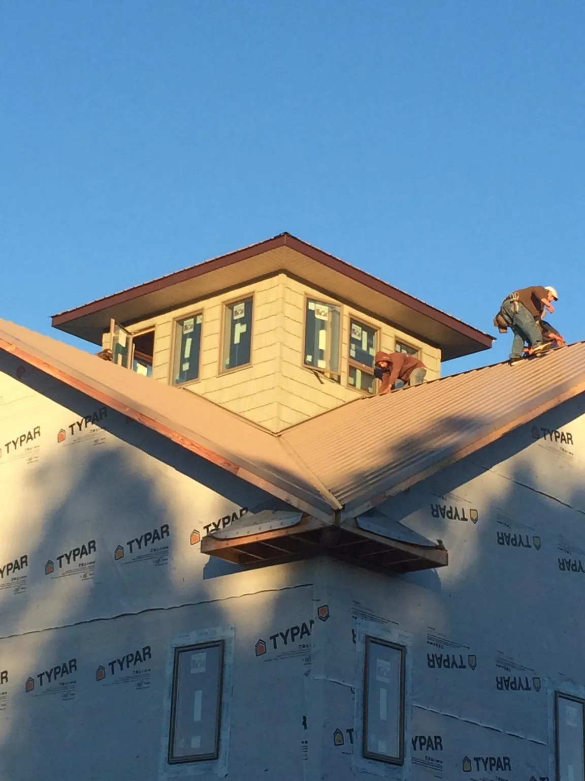 Roofers working around a rooftop cupola on a new metal roof at sunset — Roof Waterproofing in Boulder City by Roofing Brothers